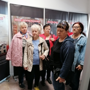 Stojący członkowie klubu dyskusyjnego "Seniorzy z książką na ty" w trakcie wizyty w Izbie Pamięci Żołnierzy Niezłomnych w Witaniowie
