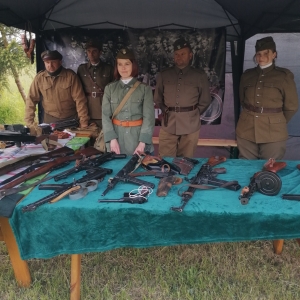 Stojący  pod namiotem członkowie Grupy Rekonstrukcyjno-Historycznej im. cc. mjr „Zapory” prezentujący broń historyczną na festynie w Witaniowie.