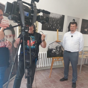 Stojący Wicestarosta Łęczyński - Michał Pelczarski w trakcie nagrania programu dla TVP 3 Lublin w Izbie Pamięci.