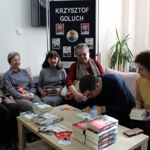 Krzysztof Goluch oraz pięć pań z DKK w Cycowie siedzących na kanapach, autor wpisuje dedykację do książki.