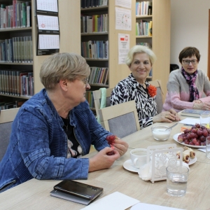 Wnętrze biblioteki, trzy uczestniczki w trakcie spotkania Dyskusyjnego Klubu Książki.